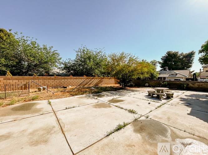 A concrete area with a fence and trees in the background.