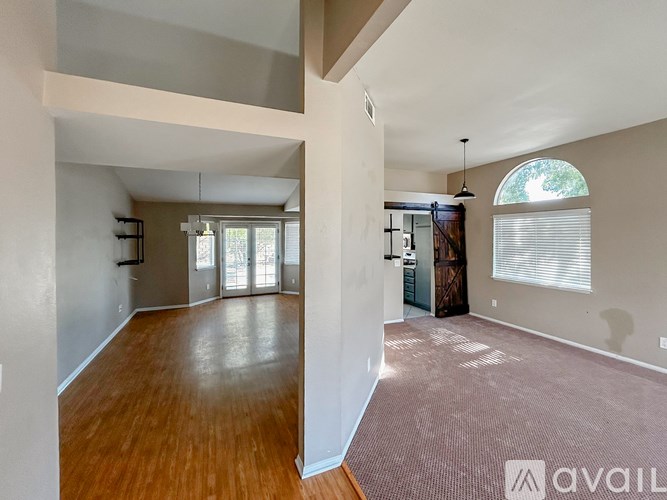 A spacious room with wooden floors and a large window.