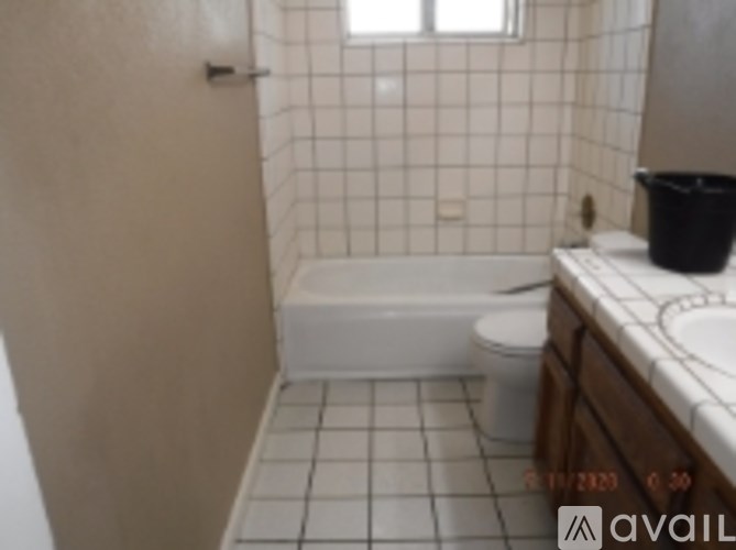 A white bathtub sits in a bathroom with a toilet and sink.