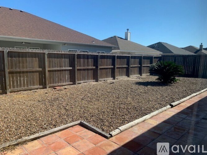 A backyard with a gravel area and a brick border.