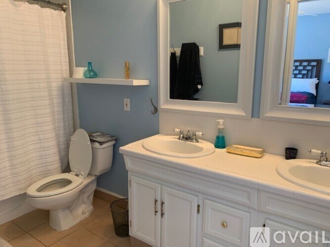 A bathroom with a toilet, sink, and mirror.