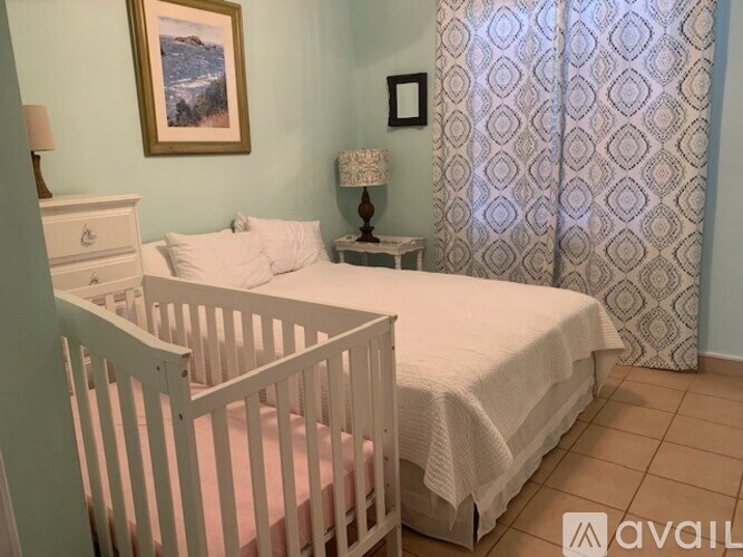 A baby's room with a white crib and a white bed with a white blanket.