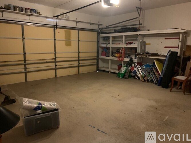 A storage room with a white shelving unit and a grey plastic bin on the floor.