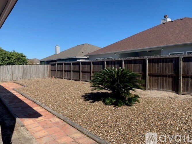 A backyard with a wooden fence and a gravel area.