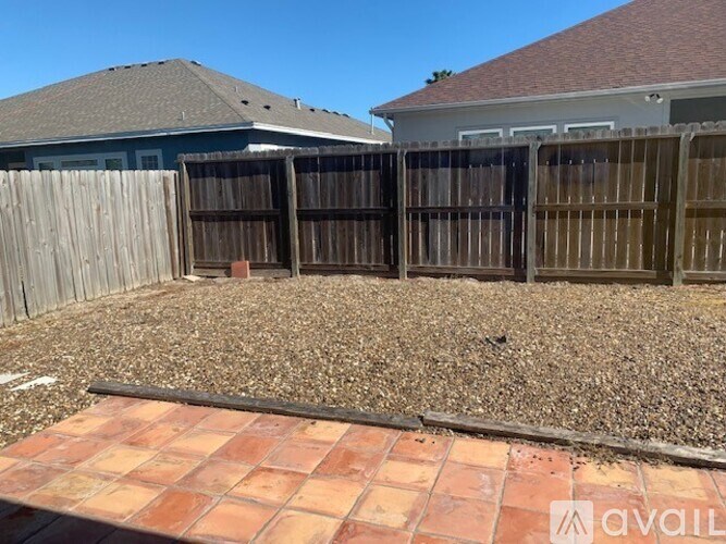 A backyard with a gravel area and a wooden fence.