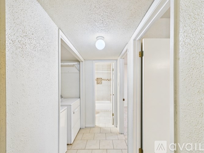 A white hallway with a light on the ceiling and a door on the right.