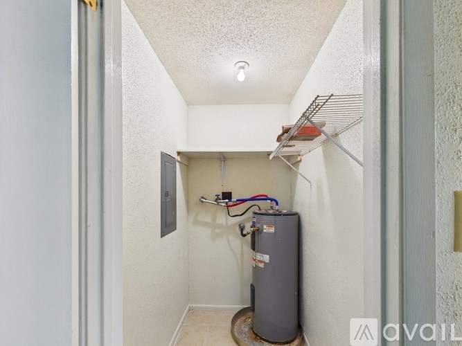 A utility closet with a water heater and electrical wires.