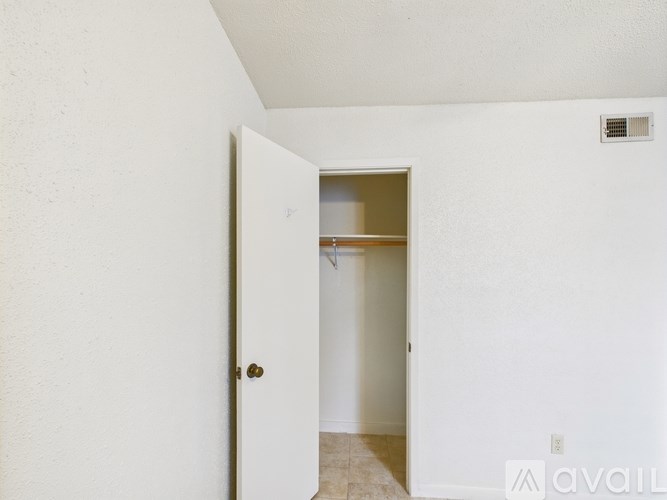 A white door with a gold handle is open to a small room with a shelf.