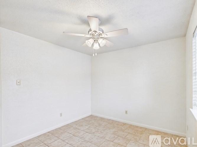 A room with a ceiling fan and tiled floor.