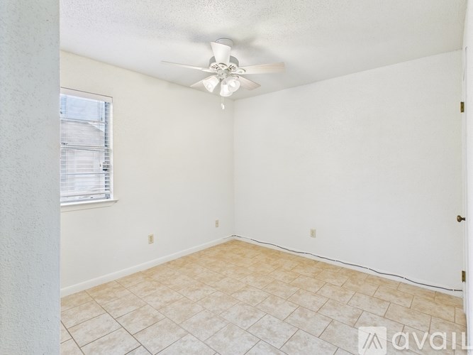 A room with a ceiling fan and tiled floor.
