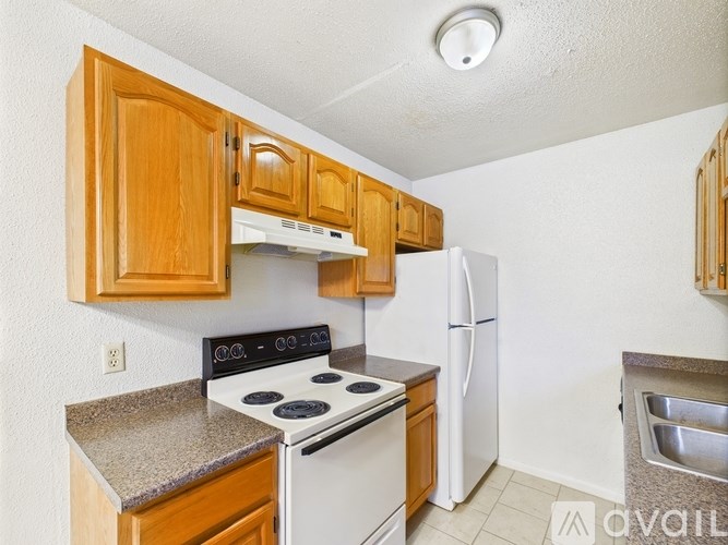 A kitchen with a white stove top oven and white refrigerator.