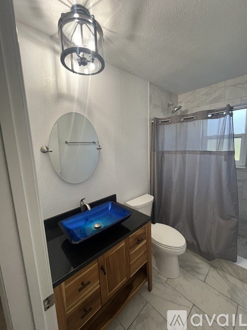 A bathroom with a blue sink and a round mirror.
