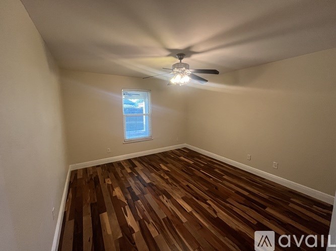 A room with wooden flooring and a ceiling fan.