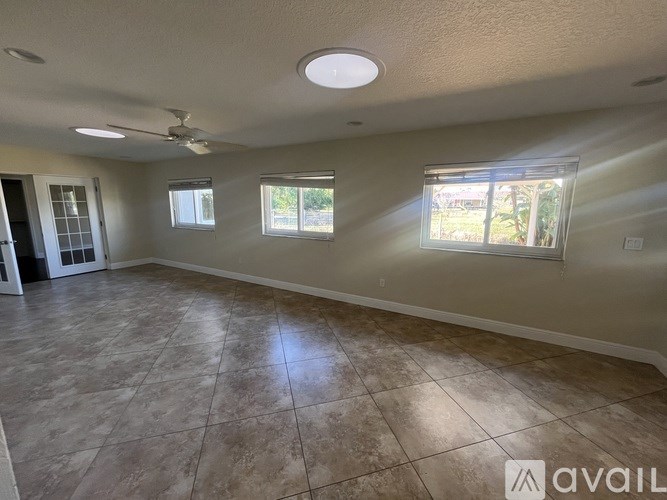 A spacious room with tile flooring and a ceiling fan.