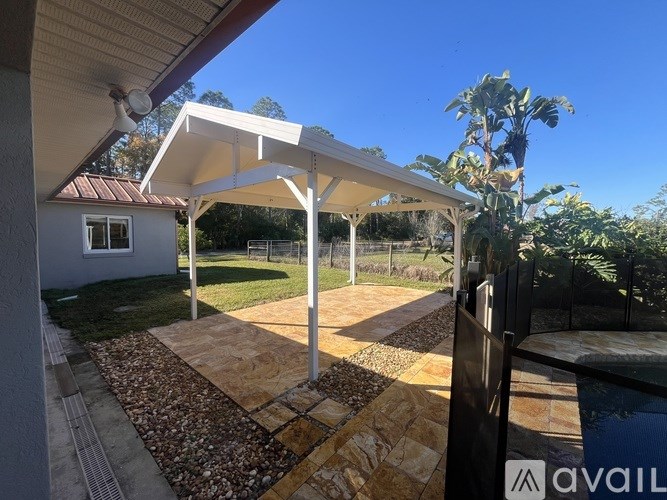 A patio with a white roof and a stone pathway.