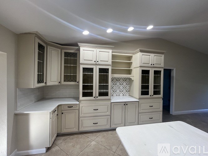 A kitchen with white cabinets and a refrigerator.