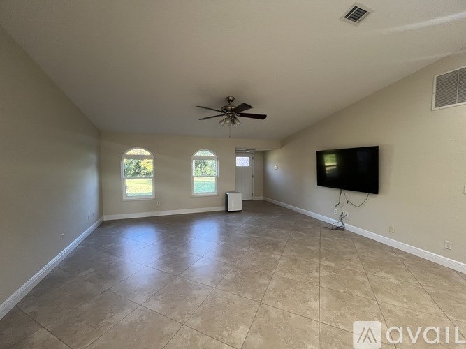 A spacious room with a ceiling fan and a flat screen TV mounted on the wall.