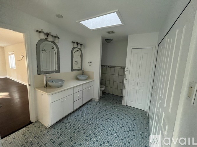 A bathroom with a sink, mirror, and tiled floor.