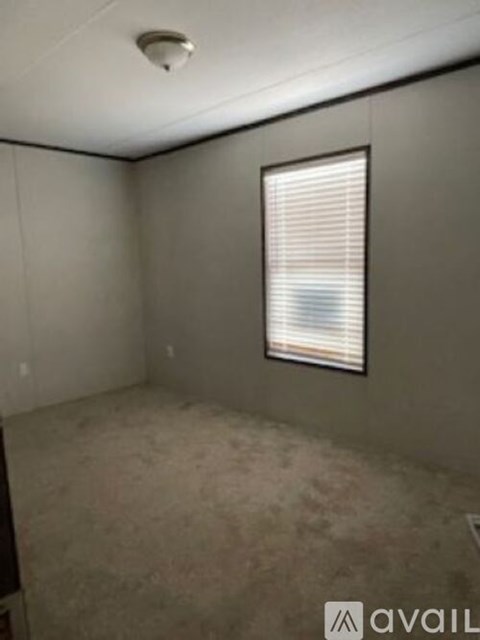 A room with a window covered in blinds and a smoke detector on the ceiling.