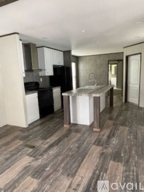 A kitchen with wooden floors and a black refrigerator.