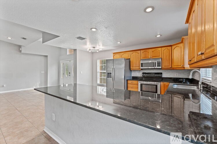 A kitchen with a granite countertop and wooden cabinets.