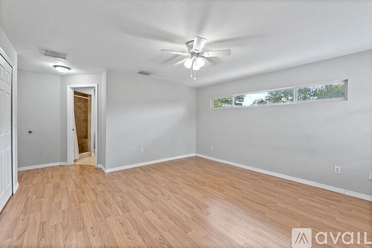 A room with a ceiling fan and wooden flooring.