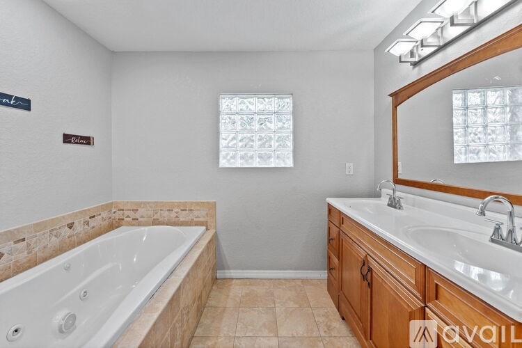A bathroom with a tub, sink, and mirror.