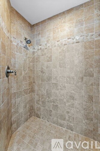 A shower with a tile wall and a faucet.