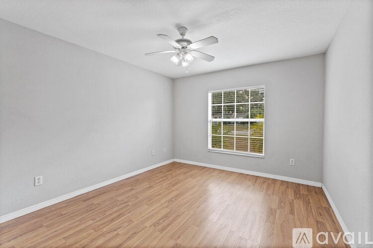 A room with a ceiling fan and a window with blinds.