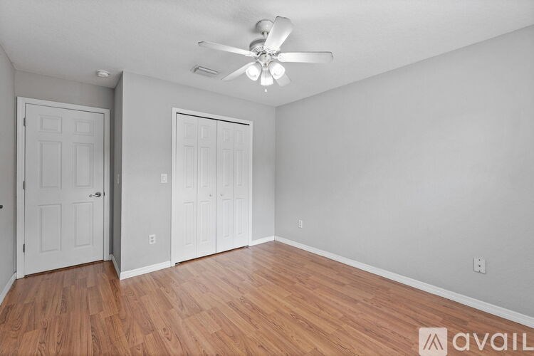 A room with a ceiling fan and two doors.