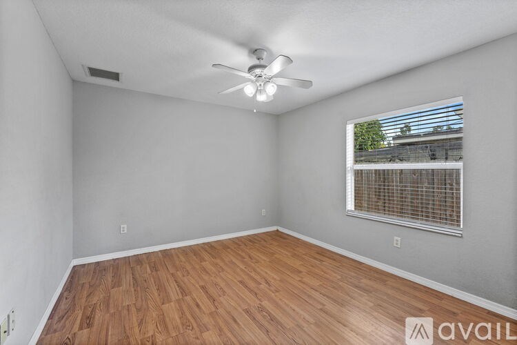 A room with a ceiling fan and wooden flooring.