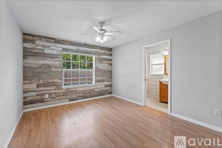 A room with wooden flooring and a window with blinds.