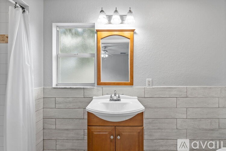 A bathroom with a sink, mirror, and shower curtain.