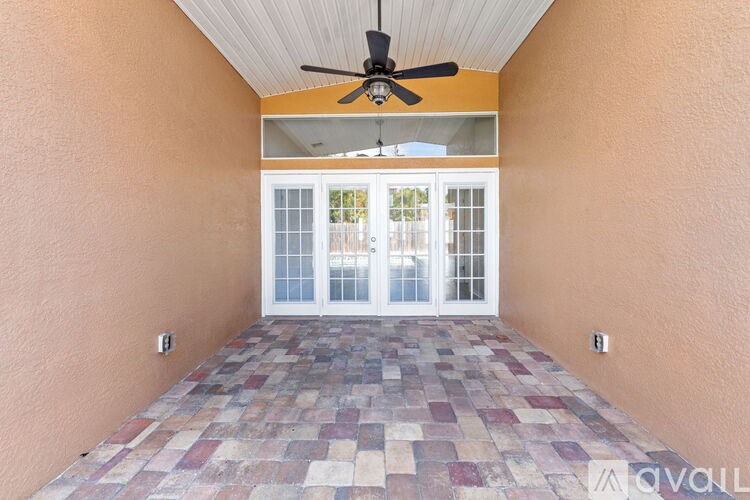 A patio with a ceiling fan and tiled floor.