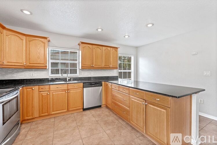 A kitchen with wooden cabinets and black countertops.
