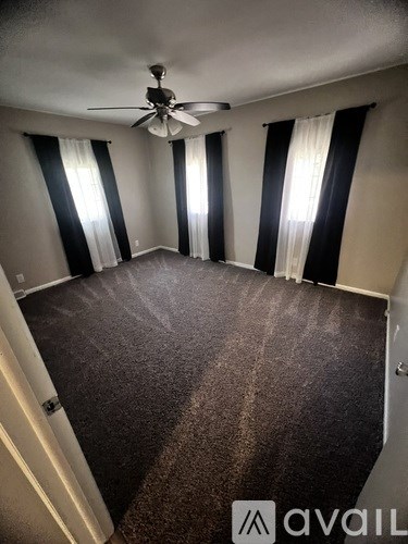 A room with a carpeted floor and a ceiling fan.