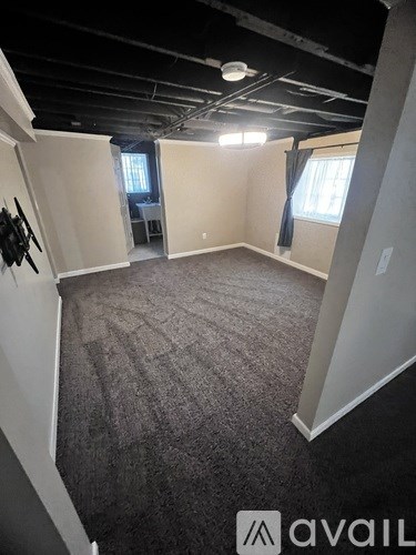 A room with a carpeted floor and a window with curtains.
