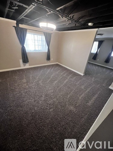 A room with a carpeted floor and a window with curtains.