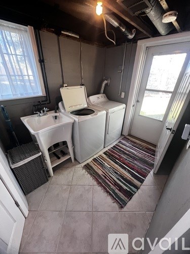 A bathroom with a toilet, sink, and a window.