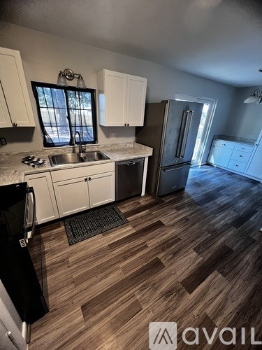 A kitchen with wooden floors and white cabinets.