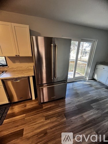 A kitchen with a stainless steel refrigerator and a wooden floor.