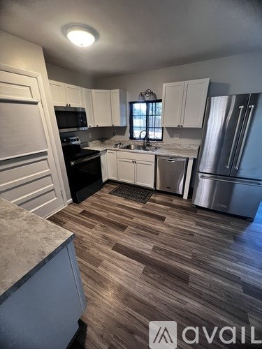 A kitchen with white cabinets and a wooden floor.