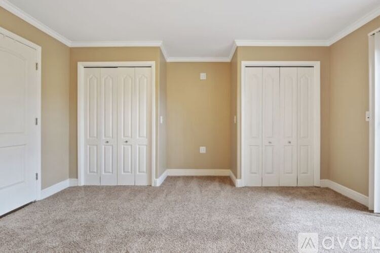 A room with carpeted floor and two white doors.
