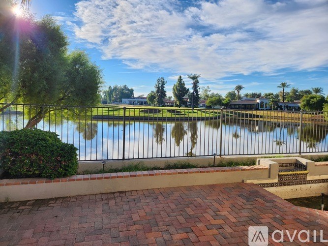 A sunny day at a park with a lake and a fence.