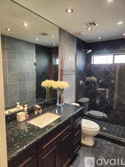 A bathroom with a sink, toilet, and a large mirror.
