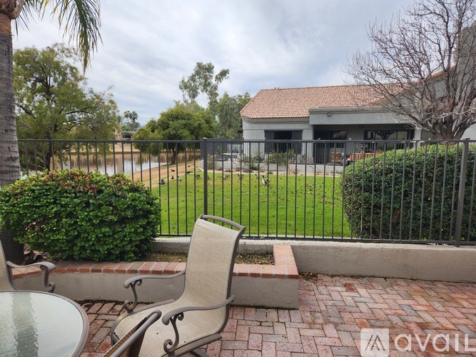 A patio with a table and chairs overlooks a fenced yard.