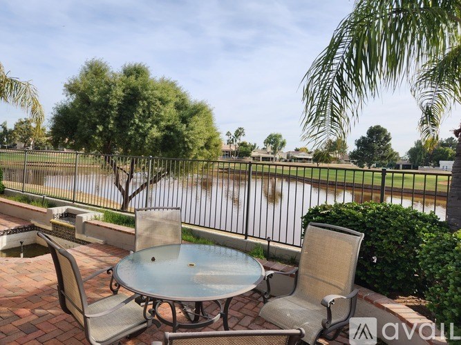 A patio with a table and chairs overlooking a pool.