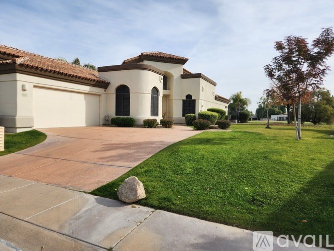 A house with a driveway and a large rock in the middle of it.