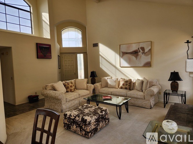 A living room with a couch, chair, ottoman, and a painting on the wall.