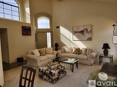 A living room with a couch, chair, ottoman, and a painting on the wall.